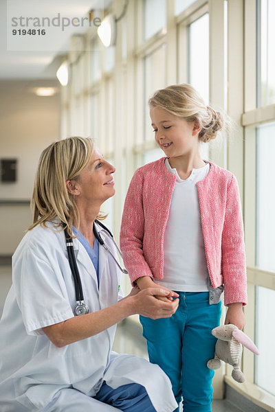 Ärztin im Gespräch mit einem Mädchen im Flur eines Krankenhauses