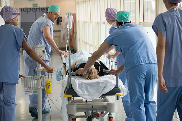 Medizinisches Fachpersonal schiebt den Patienten auf die Trage in einem Krankenhaus