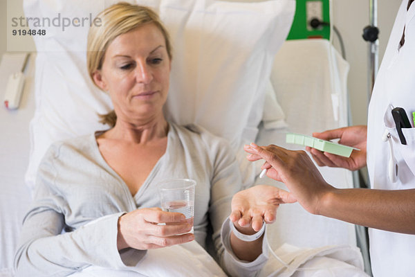 Krankenschwester gibt dem Patienten auf dem Krankenhausbett Pille