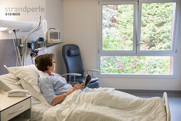 Frau schaut durch ein Fenster auf das Krankenhausbett