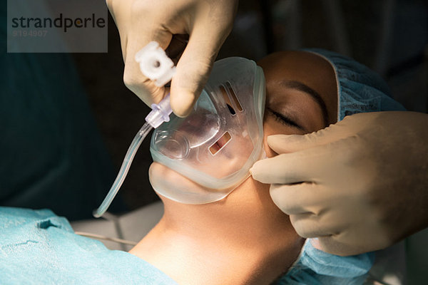Anästhesist mit Sauerstoffmaske über dem Mund des Patienten im Operationssaal