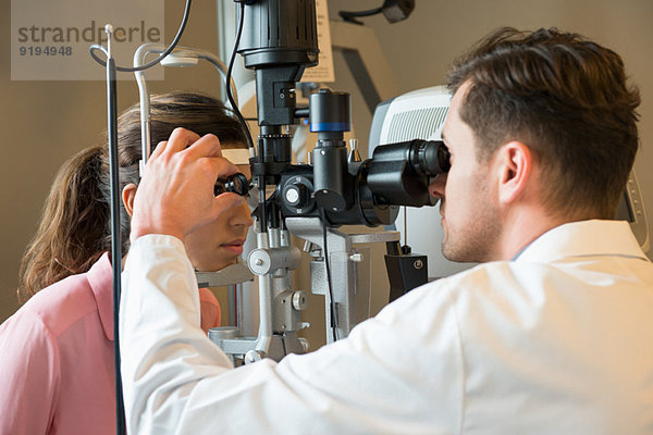Männlicher Optiker untersucht die Augen der Frau