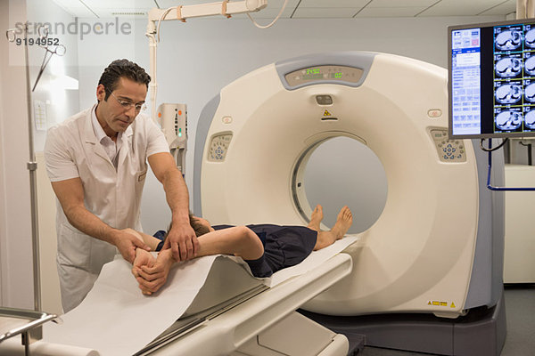 Männlicher Arzt bereitet Patient für MRT-Scan im Krankenhaus vor