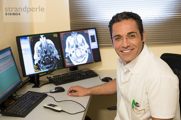 Männlicher Arzt untersucht Gehirn-MRT-Scan am Computer