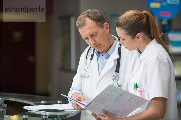 Zwei Ärzte besprechen medizinischen Bericht an der Rezeption des Krankenhauses