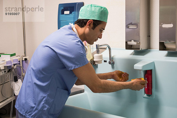 Chirurg beim Händewaschen mit Desinfektionsmittel Betadine im Operationssaal