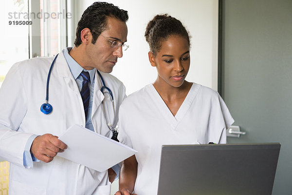 Arzt und Krankenschwester besprechen Aufzeichnung auf einem Laptop im Krankenhaus