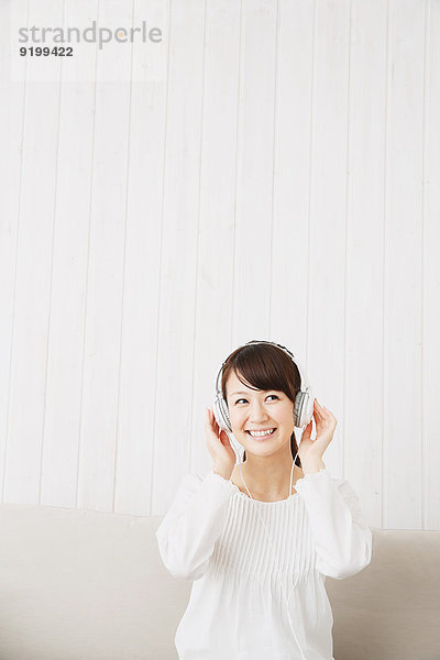 junge Frau junge Frauen Couch weiß Hemd Kopfhörer japanisch