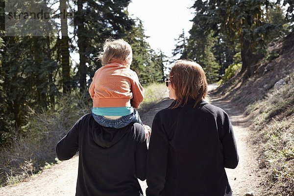 Frauen gehen durch den Wald in Oregon  USA  mit Kleinkind auf den Schultern.