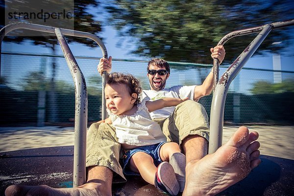 Vater und Kleinkind-Tochter drehen sich im Parkkreisverkehr