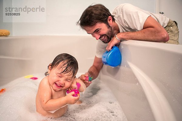 Vater und Kleinkind spielen beim Baden