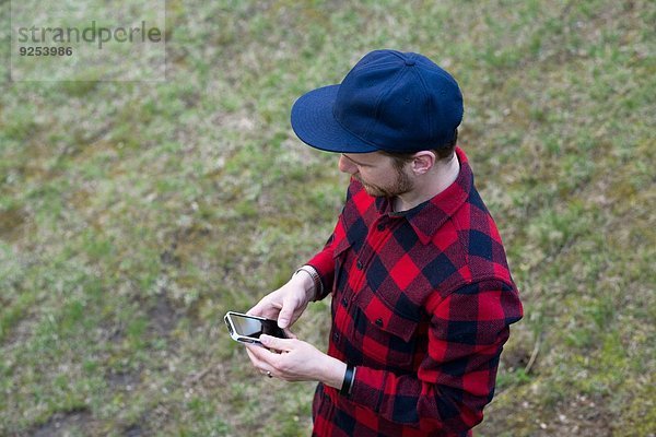 High-Winkel-Ansicht der mittleren Erwachsenen Mann SMS auf dem Smartphone