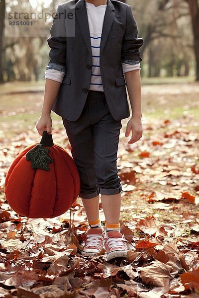 Abgeschnittenes Bild des Jungen im Wald mit Kürbiskopf