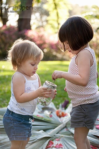 Mädchen und Kleinkind Schwester mit grüner Anole Eidechse und Glas im Garten