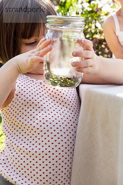 Mädchen hält Glas mit grüner Anole Eidechse im Garten