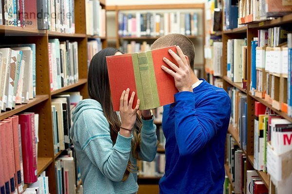 Junges Paar versteckt sich hinter dem Buch