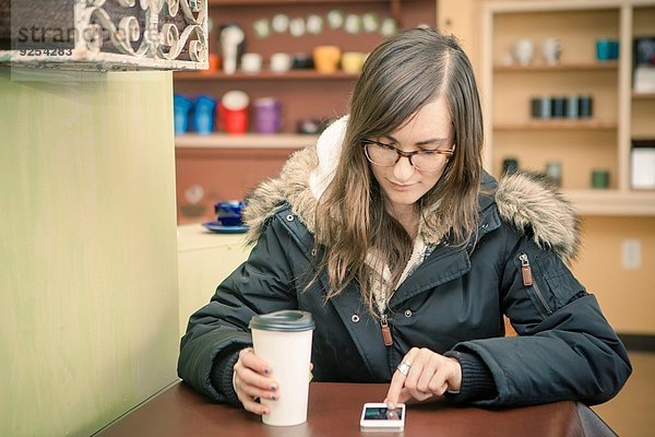Mid Erwachsene Frau SMS auf dem Smartphone im Cafe
