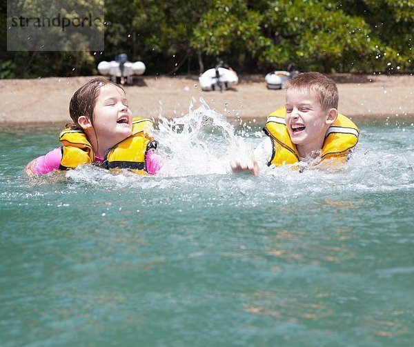 Bruder und Schwester spielen kämpfen und planschen im Meer.