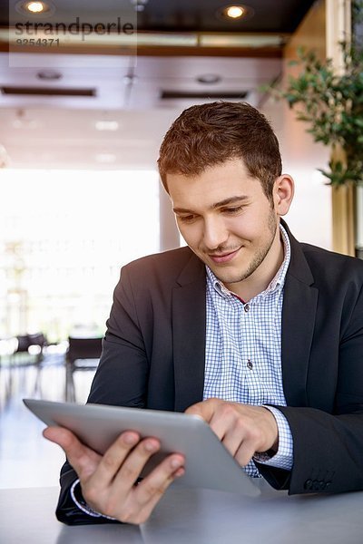 Junger Mann im Büro mit Touchscreen auf digitalem Tablett