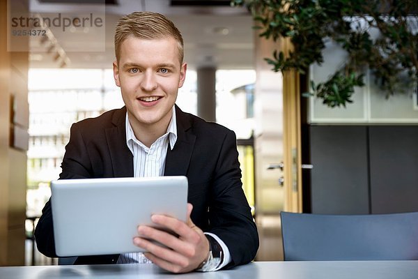Porträt eines jungen Mannes im Büro mit Touchscreen auf digitalem Tablett