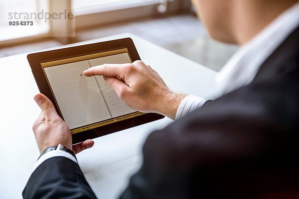 Nahaufnahme des jungen Mannes im Büro mit Touchscreen auf digitalem Tablett