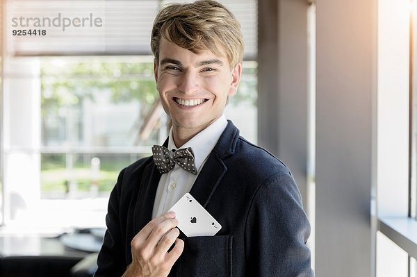 Porträt eines jungen Geschäftsmannes mit einer Ass-Spielkarte in der Tasche