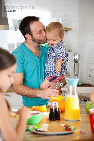Mittlerer Erwachsener Mann multi tasking Frühstück mit Sohn und Tochter