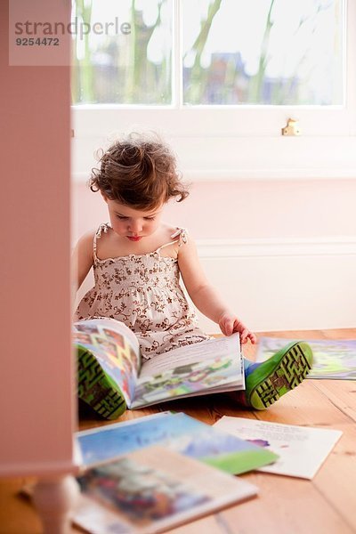 Weibliches Kleinkind liest Märchenbücher im Schlafzimmer