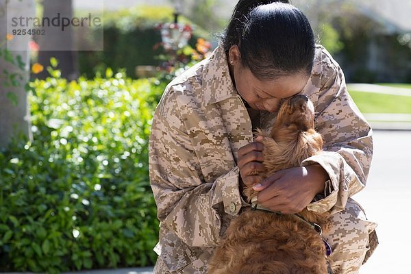 Soldatin umarmt Haushund auf der Straße beim Homecoming