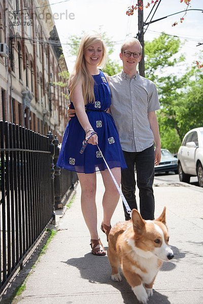 Junges Paar geht mit Corgi Dog auf der Straße spazieren