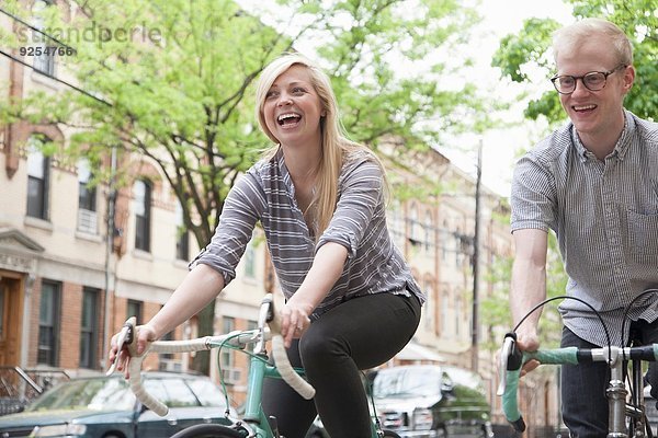 Junges Paar lacht beim Radfahren auf der Straße