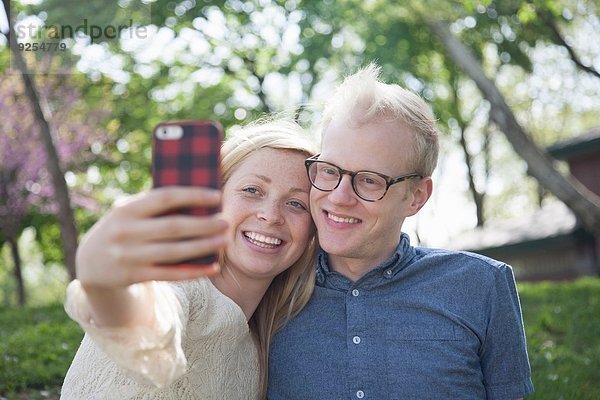 Junges Paar im Park nimmt Selfie mit Smartphone