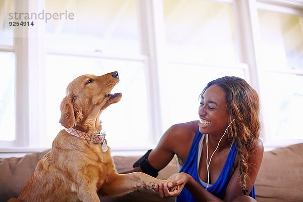 Junge Frau bei einer Trainingspause  Streichelhund im Wohnzimmer