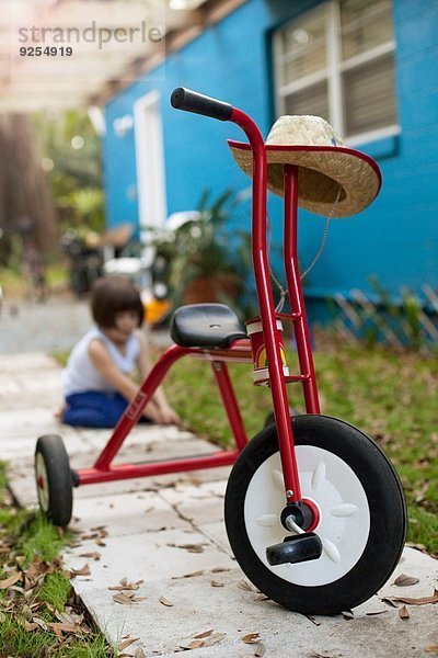 Dreirad vor dem vierjährigen Mädchen auf dem Gartenweg