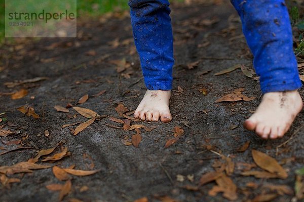 Schlammfuß eines vierjährigen Mädchens im Gartenboden stehend