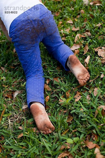 Vierjähriges Mädchen krabbelt in der Taille auf Gartengras