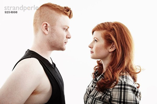 Studio-Porträt eines rothaarigen jungen Paares  das von Angesicht zu Angesicht blickt.