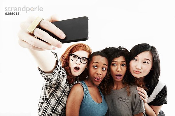 Studio-Porträt von vier jungen Frauen  die Selfie auf dem Smartphone nehmen