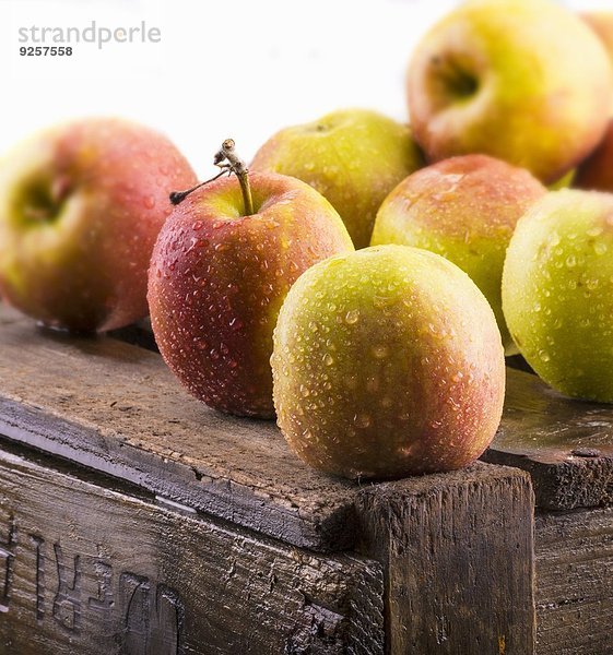 Mehrere Äpfel mit Wassertropfen auf Holzkiste