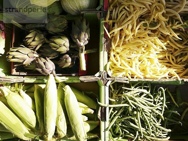 Artischocken  Bohnen und Maiskolben in Steigen auf dem Markt