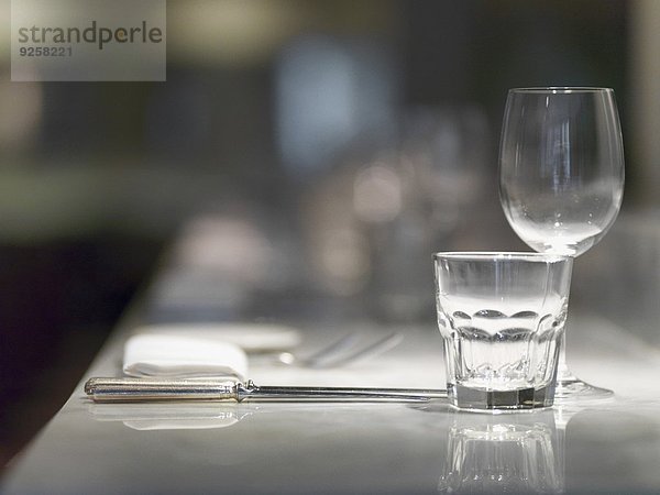 Gedeck mit Gläsern  Besteck und Serviette auf Restauranttisch