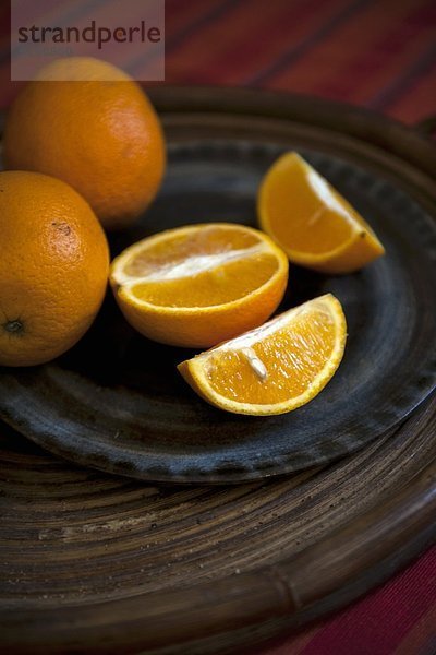Orangen  ganz und aufgeschnitten  auf Teller
