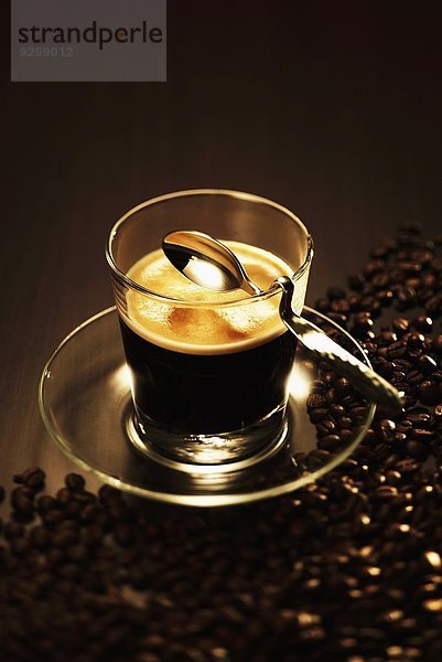 Ein Glas Espresso mit Löffel und Kaffeebohnen