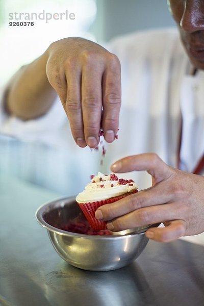 Red Velvet Cupcakes mit Zucker bestreuen