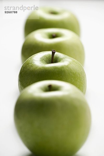 Vier grüne Äpfel in einer Reihe