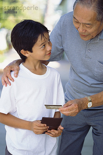 Senior Senioren Mann geben Enkelsohn Kredit Kreditkarte Karte