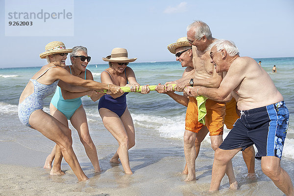 Senior Senioren Freundschaft Strand spielen Tauziehen