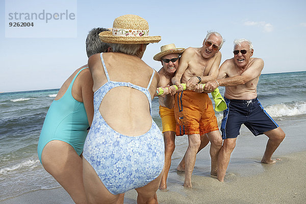 Senior Senioren Freundschaft Strand spielen Tauziehen