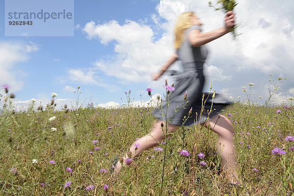 Junge Frau läuft auf Wildblumenwiese