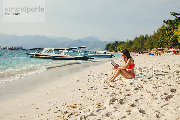 Indonesien  Gili-Inseln  Frau beim Lesen eines Buches am Strand
